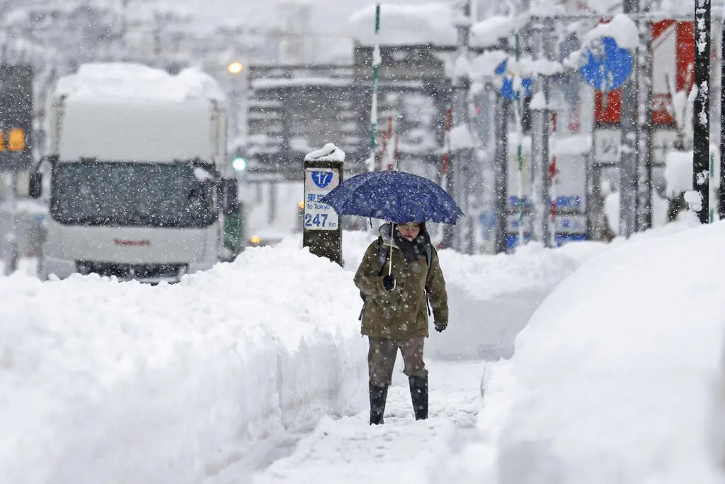 Una mujer avanza en medio de una fuerte nevada, el martes 20 de diciembre de 2022 en Uonua, prefectura de Niigata, en el norte de Japón.(Kyodo News via AP)