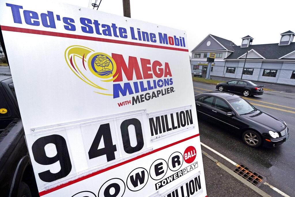 Dos autos pasan frente a un letrero que indica el premio mayor de la lotería Mega Millions afuera de la gasolinera Teds State Line Mobil, el jueves 5 de enero de 2023, en Methuen, Massachusetts. (AP Foto/Charles Krupa)