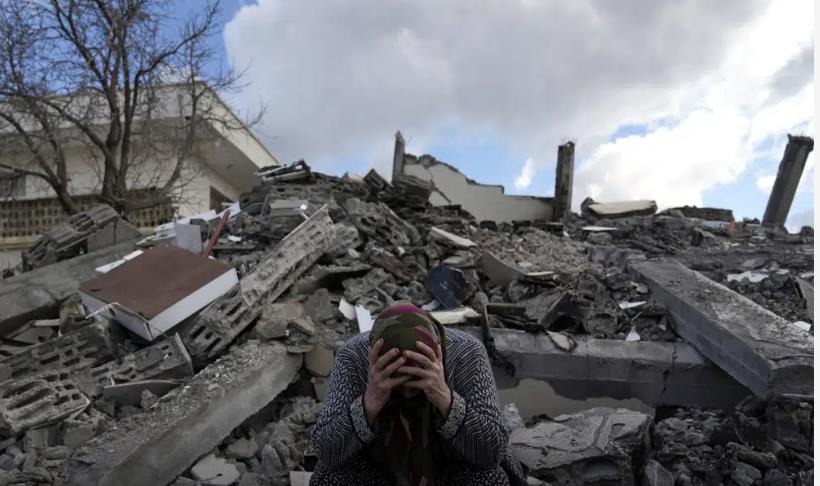 Una mujer sentada sobre los escombros de un edificio que se derrumbó por el sismo del lunes en Nurdagi, sur de Turquía. (AP Foto/Khalil Hamra)