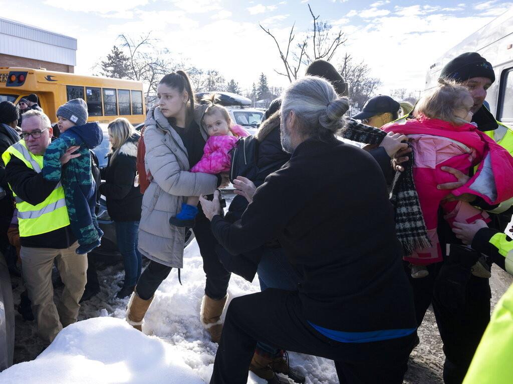Varios padres abrazan a sus hijos pequeños luego de que un autobús embistió a una guardería el 8 de febrero de 2023, en Laval, provincia de Québec, Canadá. (Ryan Remiorz/The Canadian Press vía AP)