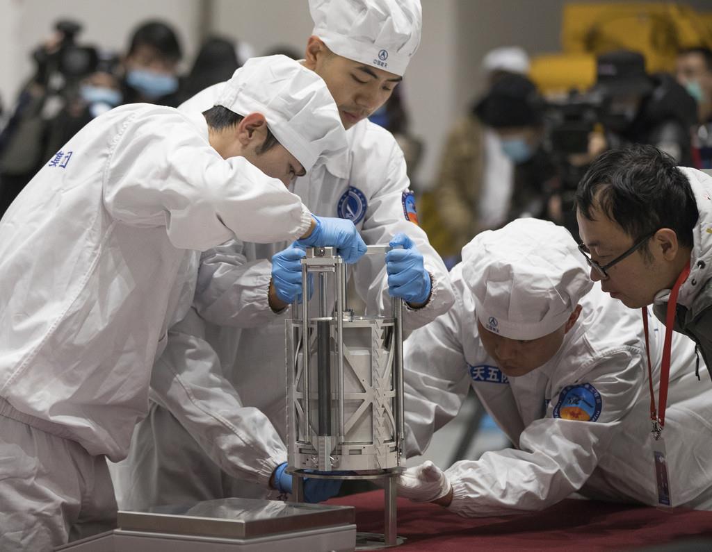 Fotografía del jueves 17 de diciembre de 2020 proporcionada por la agencia de noticias Xinhua de China de técnicos preparándose para pesar un contenedor con muestras lunares recopiladas por el módulo de aterrizaje Change 5 de China en Beijing. (Jin Liwang
