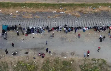 Duermen migrantes al lado del muro fronterizo de Tijuana