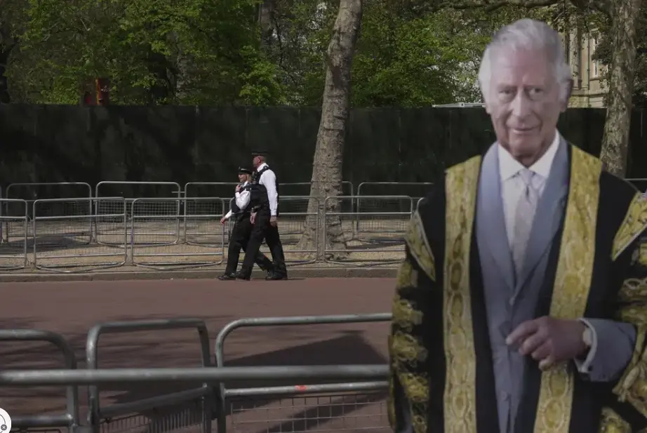 Agentes de la policía vigilan una calle detrás de un cartón con la imagen del rey Carlos III, en Londres, días antes de la coronación del monarca británico. (AP Foto/Kin Cheung)