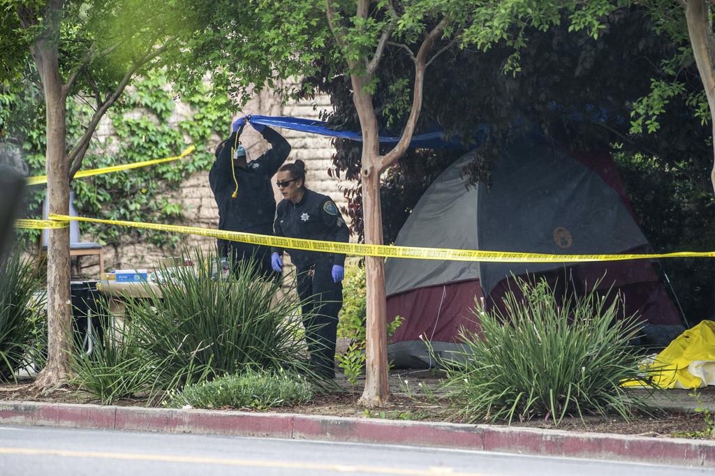 Policías investigan en el lugar en donde una indigente fue apuñalada varias veces a través de un costado de su tienda de campaña cerca de las calles 2nd y L, el martes 2 de mayo de 2023, en Davis, California. (Hector Amezcua/The Sacramento Bee via AP)