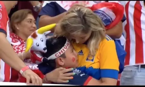 En la toma que se vio en las pantallas al finalizar el partido de vuelta de la final, se observa a una madre fanática de Tigres, consolar a su hijo aficionado de Chivas. Foto: Especial.