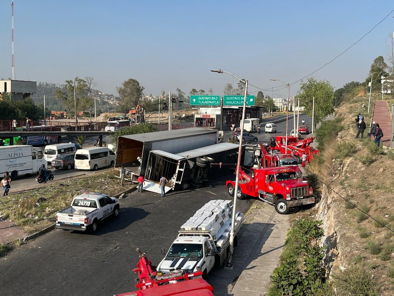 Trabajadores de la empresa comenzaron a traspalear la carga a otro tráiler y así poder con grúas enderezar la pesada unidad. Foto: Israel Lorenzana.