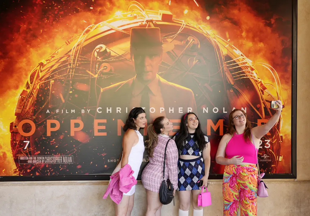 Kayla Seffing, Maddy Hiller y Casey Myer se toman una selfie frente a un cartel de la película Oppenheimer antes de asistir a una proyección anticipada de Barbie, el jueves 20 de julio de 2023 en los cines AMC The Grove 14 en Los Ángeles. (Foto AP/Chri