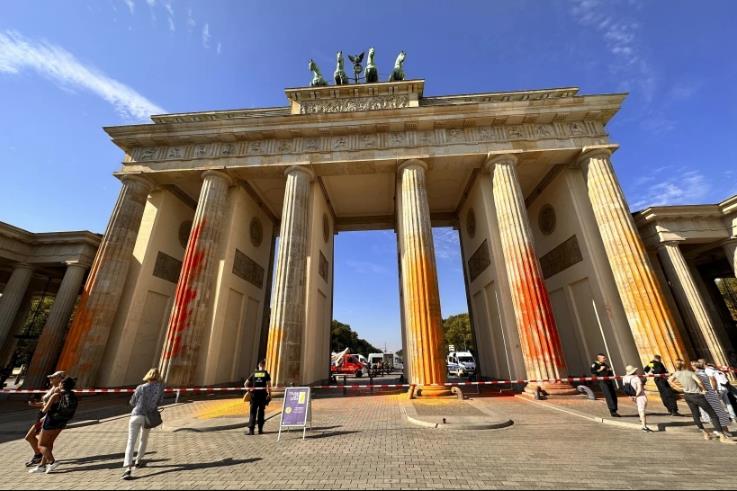 Integrantes del grupo activista Última Generación rocían pintura naranja en la Puerta de Brandeburgo de Berlín el domingo 17 de septiembre de 2023. (Paul Zinken/dpa vía AP)