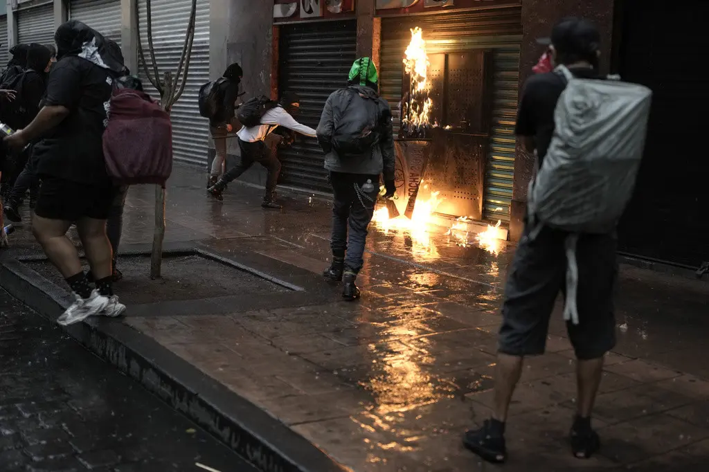 Manifestantes intentan incendiar una tienda el 2 de octubre de 2023, luego de una marcha para conmemorar el 55º aniversario de los asesinatos de estudiantes que protestaban en la plaza de Tlatelolco. (AP Foto/Eduardo Verdugo)