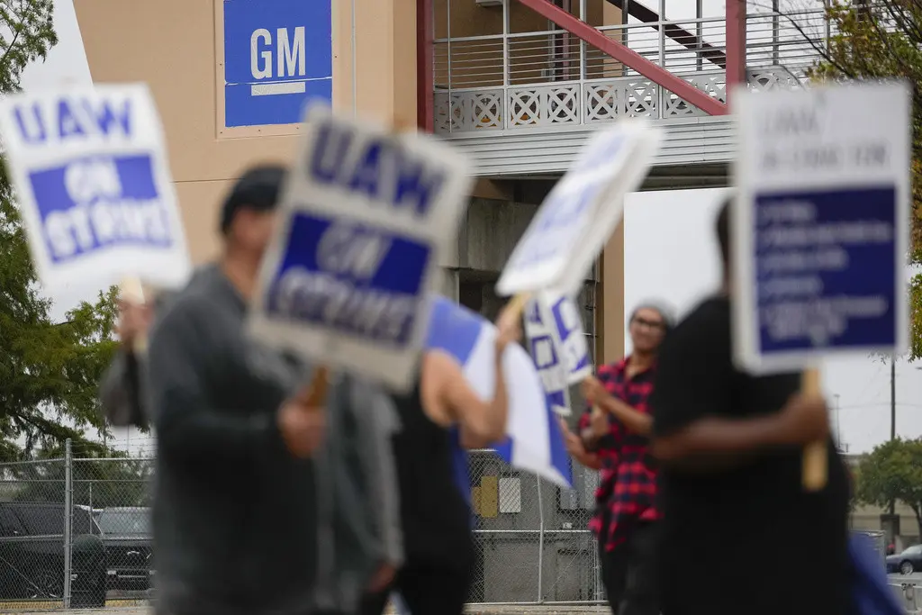 Varias personas protestan afuera de la planta de General Motors en Arlington, Texas, el martes 24 de octubre de 2023. (AP Foto/Julio Cortez)