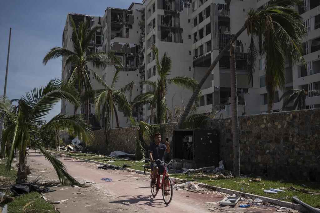 Un hombre pasa en bicicleta por una zona dañada por el huracán Otis en Acapulco, México, el domingo 29 de octubre de 2023. (AP Foto/Félix Márquez)