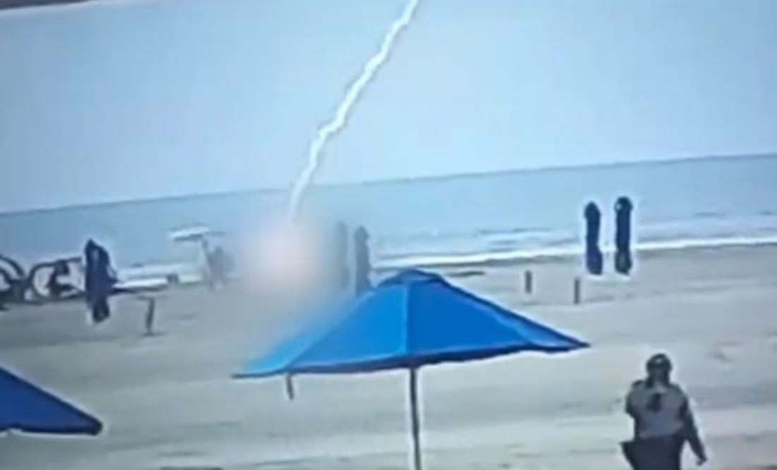 Las imágenes captadas por cámaras de videovigilancia muestran el momento en que un potente rayo alcanza a la mujer, haciendo que se desplome abruptamente sobre la arena. Foto: X @AlertaMundial2.