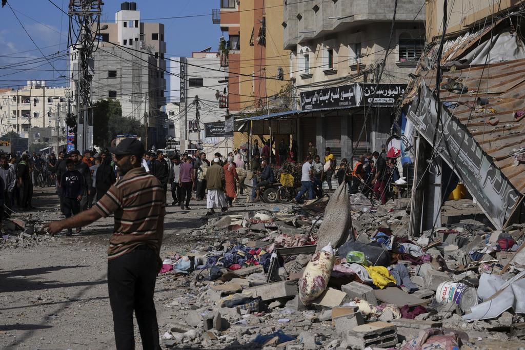 Palestinos se reúnen frente a un edificio impactado por un ataque israelí en el campo de refugiados de Nusseirat de la Franja de Gaza, el martes 21 de noviembre de 2023. (AP Foto/Adel Hana)