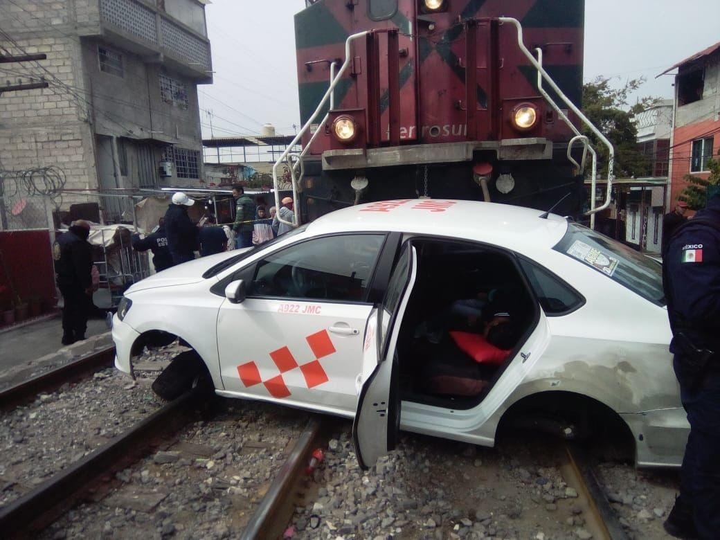 El taxi fue arrastrado por el tren, unos 50 metros, tras querer ganarle el paso; una mujer murió y dos más están heridas. Foto: Gob. de Tlalneantla