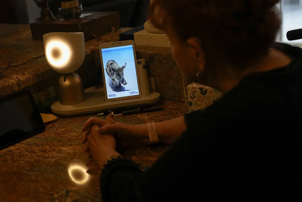 Deanna Dezern, de 83 años, interactúa con su ElliQ, un dispositivo de mesa que utiliza inteligencia artificial para mantener conversaciones similares a las humanas, el jueves 7 de diciembre de 2023, dentro de su casa en Tamarac, Florida. (AP Foto/Rebecca B