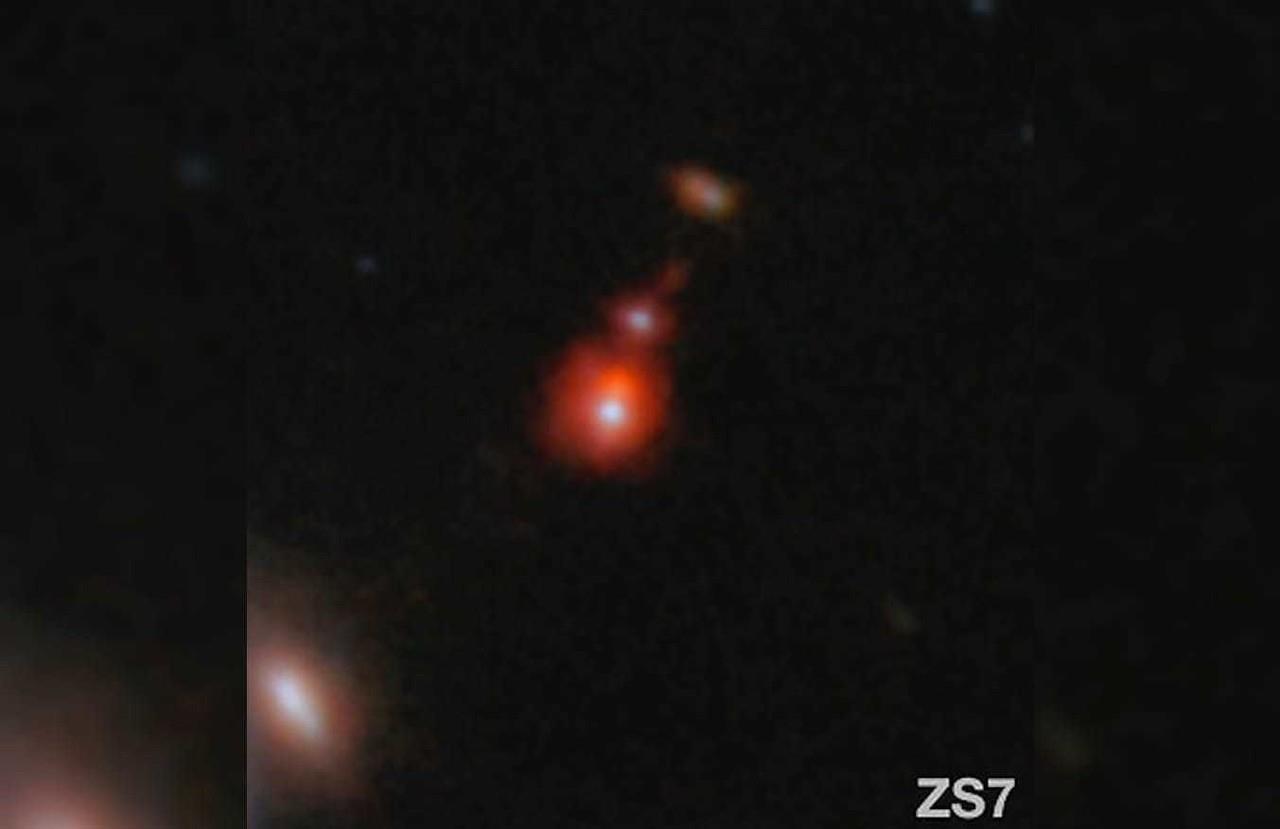 En esta imagen publicada por la NASA aparece el sistema de galaxias ZS7, que revela la emisión de hidrógeno ionizado en naranja, y la emisión de oxígeno doblemente ionizado en rojo oscuro. (ESA/Webb, NASA vía AP)