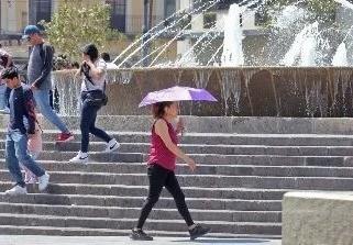 Una mujer con una sombrilla para poder protegerse del sol que hay. Foto: Informador MX.