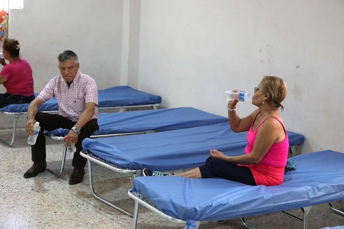 Dos personas mayores beben botellas de agua en un albergue instalado por las altas temperaturas en el municipio de San Nicolás de los Garza, Nuevo León. Foto: Jorge López