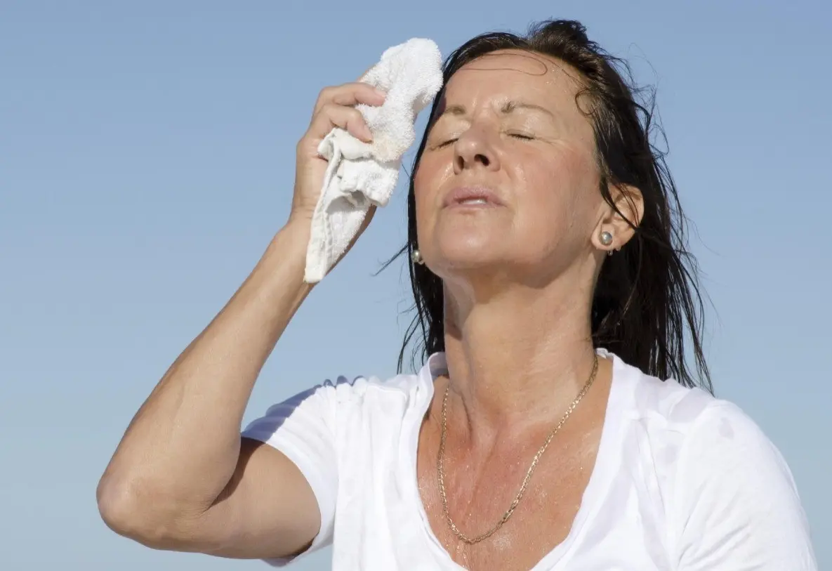 Una mujer secandose el sudor por el exceso de calor y las altas temperaturas. Foto: Medline Plus.