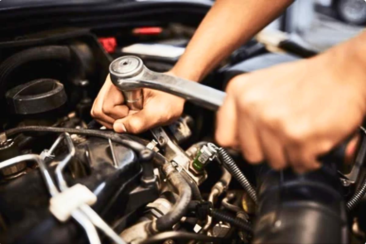 Perspectiva del motor de un automóvil y las manos de una persona mientras trabaja en su reparación. Foto: Especial