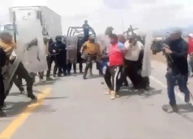 Elementos de la policía peleando con los manifestantes en la carretera. Foto: La Jornaada.