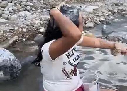 La joven de nombre Itzel dandose un baño con la poca agua que aún hay estancada en el río Santa Catarina. Foto: X @LoQuePasaEnNL.