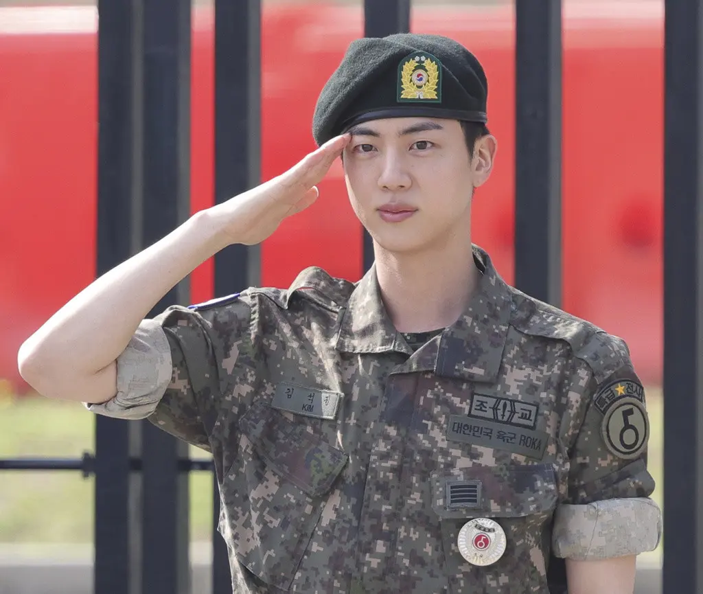 Jin, miembro de la banda de K-pop BTS, saluda después de concluir su servicio militar obligatorio afuera de una base militar en Yeoncheon, Corea del Sur, el miércoles 12 de junio de 2024. (Im Byung-shik/Yonhap vía AP)