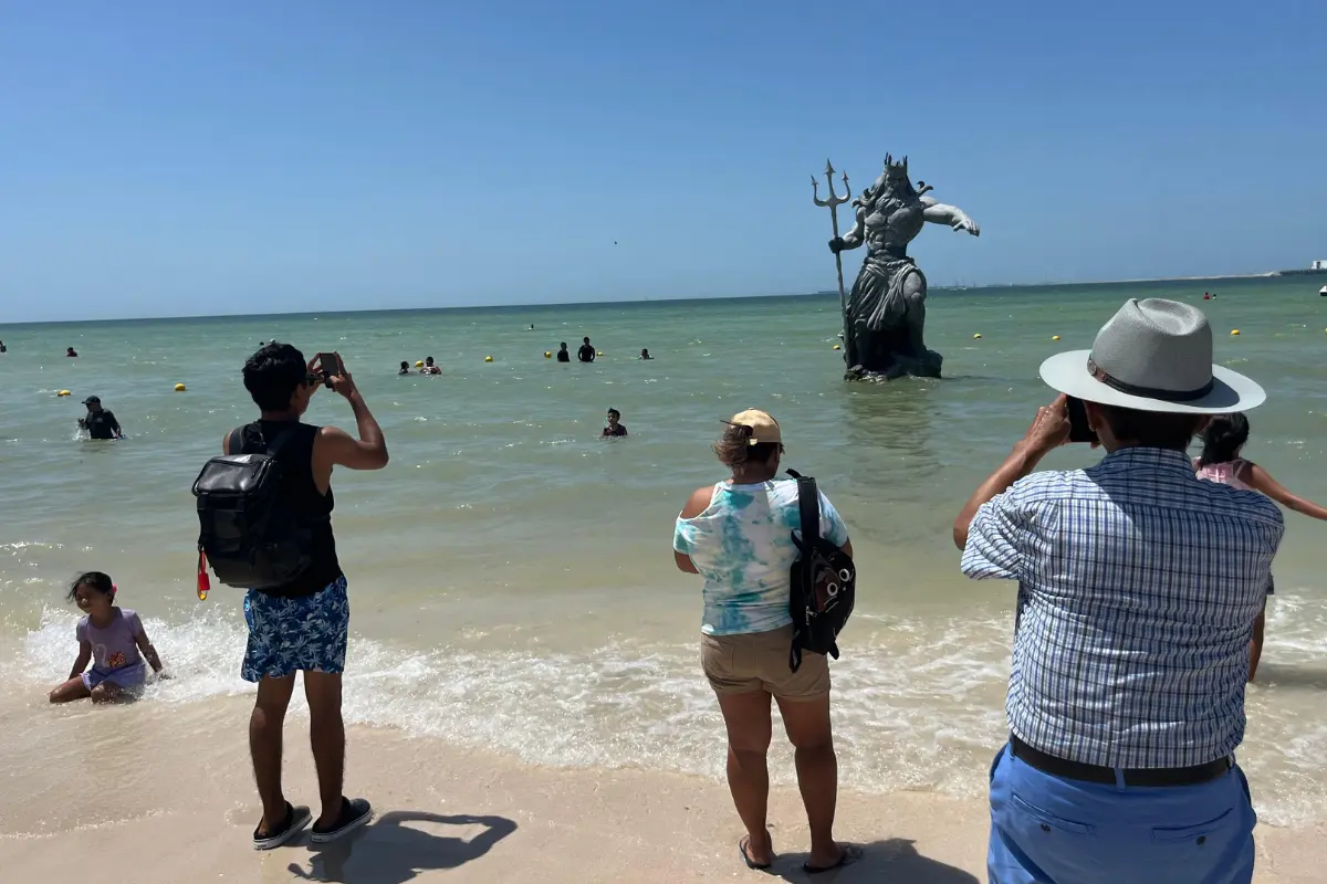 Visitantes tomando foto a la estatua de Poseidón desde la playa de puerto Progreso. Foto: Patricia Euan