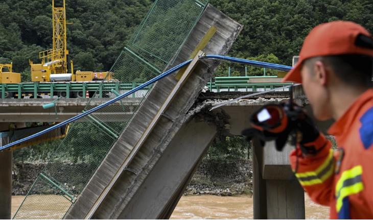 Un rescatista observa un puente derrumbado durante una operación de búsqueda y rescate en un río en el condado de Zhashui, en la ciudad de Shangluo, en la provincia noroccidental china de Shaanxi, el 20 de julio de 2024. (Zou Jingyi/Xinhua vía AP)