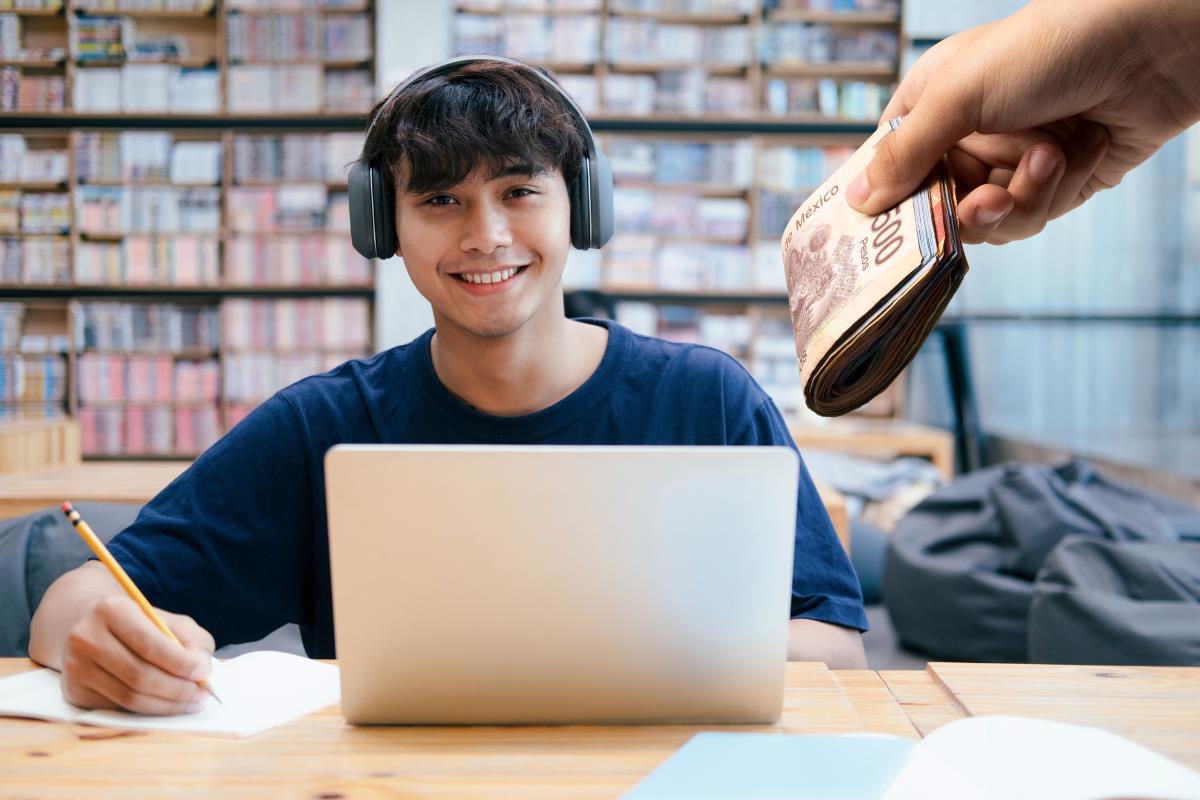 Joven en una computadora, billetes mexicanos. Foto: Especial