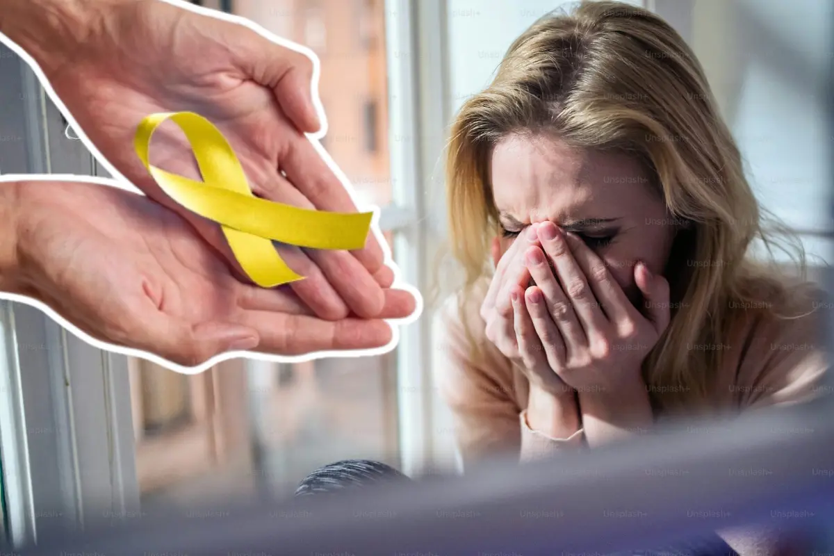 Manos sosteniendo un moño amarillo frente a una mujer llorando. Foto: Especial