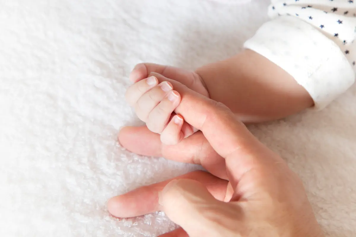 Mamá tomando de la mano a su bebé. Foto: Canva