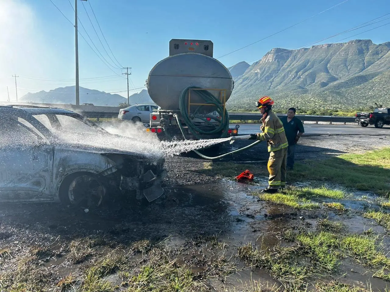 Bombero de Protección Civil sofocando el incendio del auto. Foto: Protección Civil de Nuevo León.