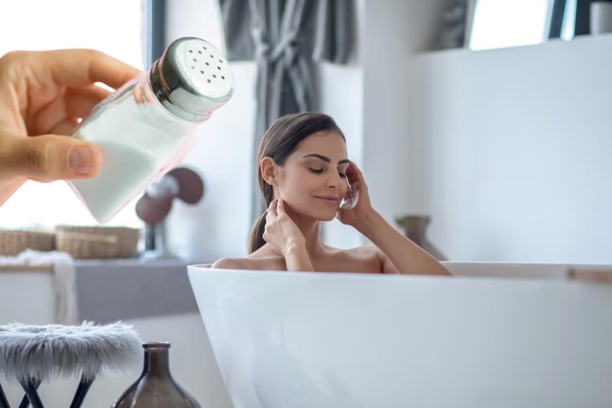 Persona en la tina de baño y una mano con un salero.   Foto: Especial