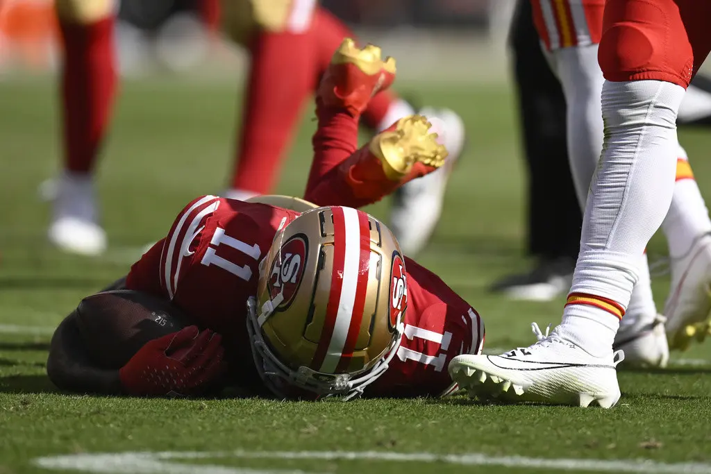 El receptor abierto de los 49ers de San Francisco , Brandon Aiyuk (11), permanece en el campo después de ser golpeado durante la primera mitad de un partido de fútbol americano. (AP Foto/Eakin Howard)