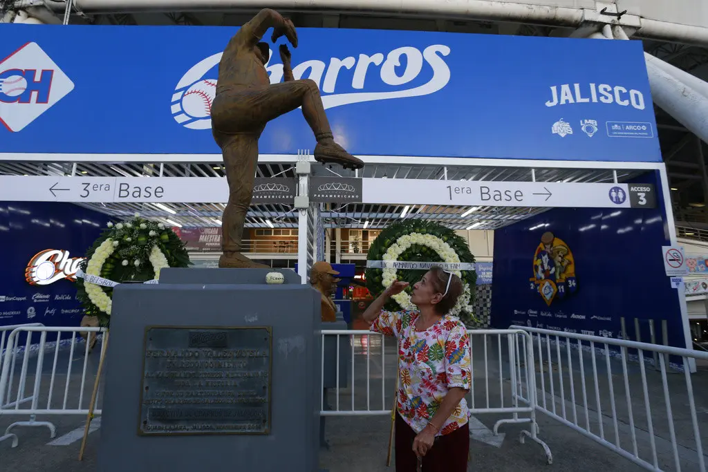 Una mujer ora junto a la estatua de Fernando Valenzuela frente al Estadio Panamericano de Guadalajara, el miércoles 23 de octubre de 2024, un día después del fallecimiento del exlanzador de los Dodgers de Los Ángeles (AP Foto/Alfredo Moya)