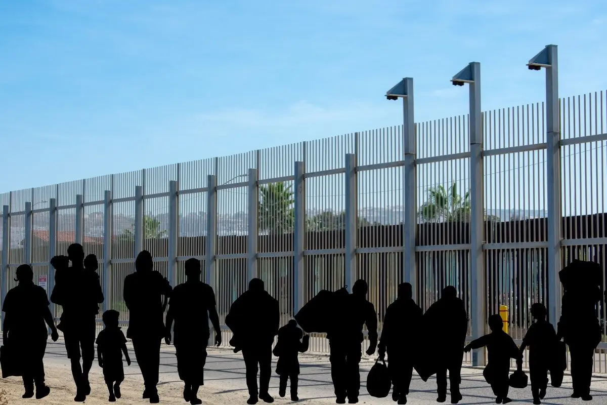 Muro fronterizo y siluetas de migrantes. Foto: Canva