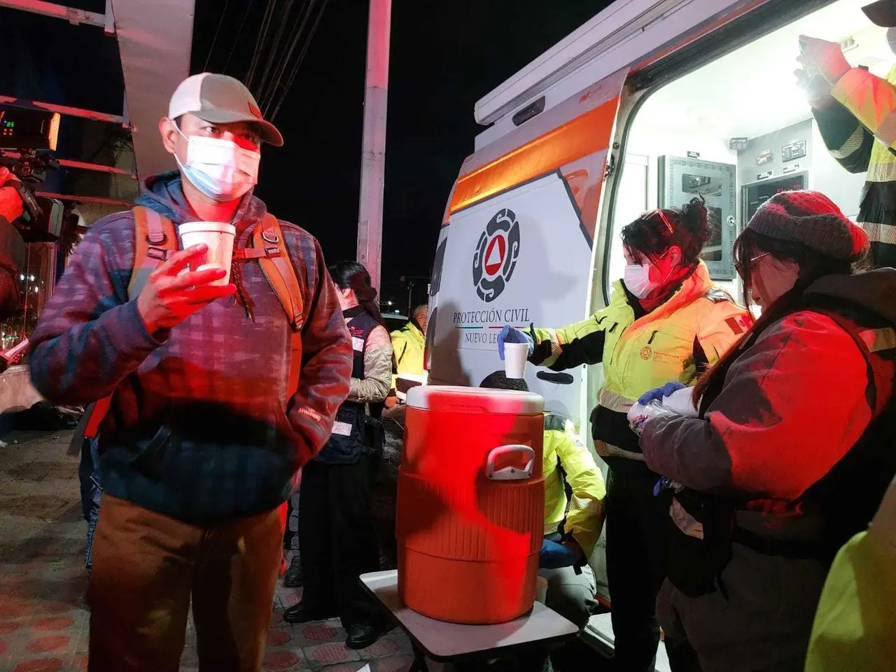 Gente recibiendo chocolate caliente para protegerse del frío. Foto: Protección Civil de Nuevo León.