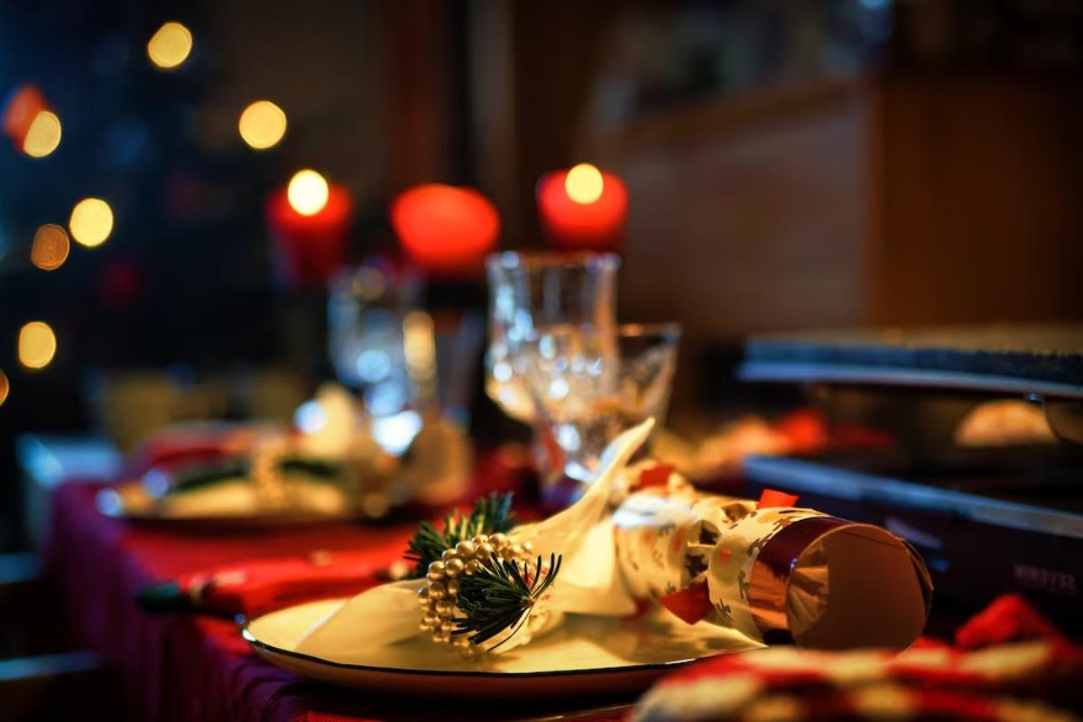 Cena de Navidad con luces rojas de fondo. Foto: Freepik editada en Canva.
