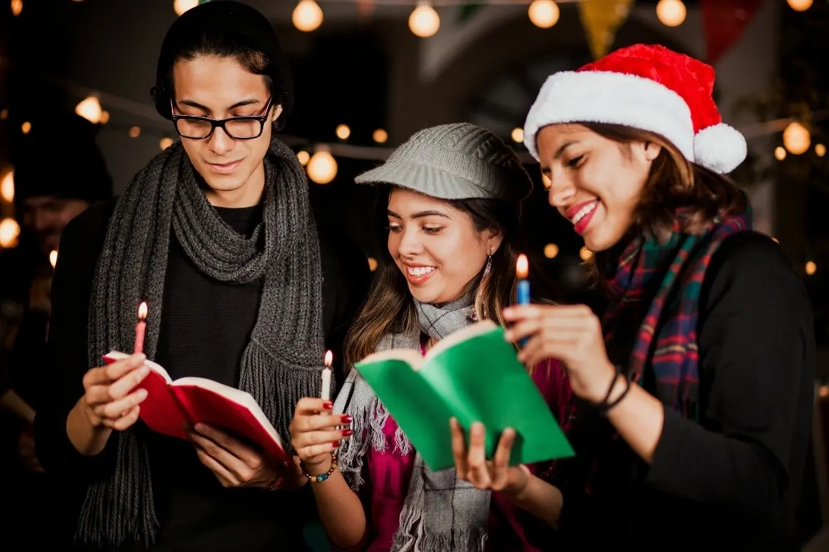 Jóvenes con velitas en Navidad. Foto: Canva