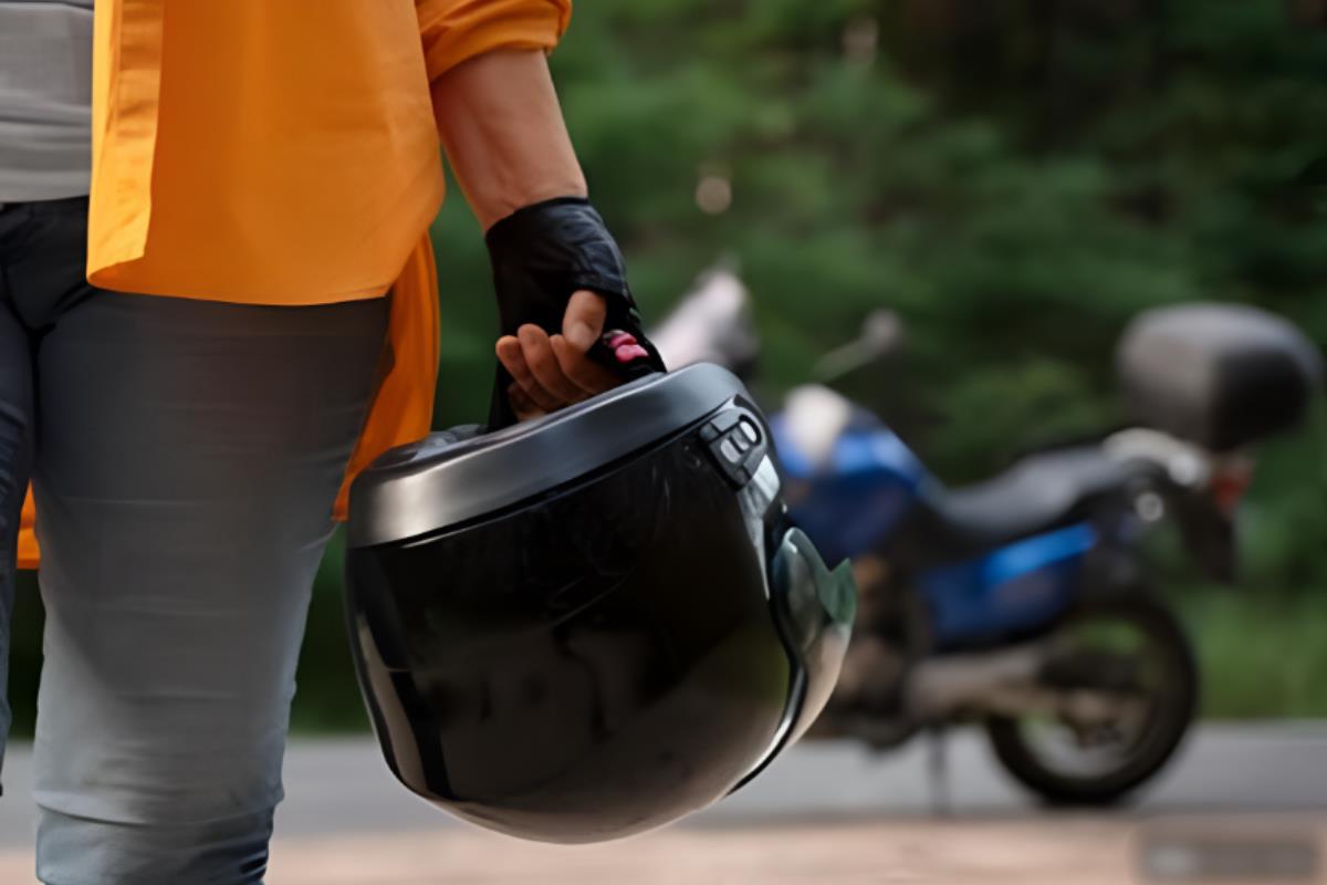 Motociclista sosteniendo un casco, frente a una moto con su casco.      Foto: Freepik, editada en Canva.