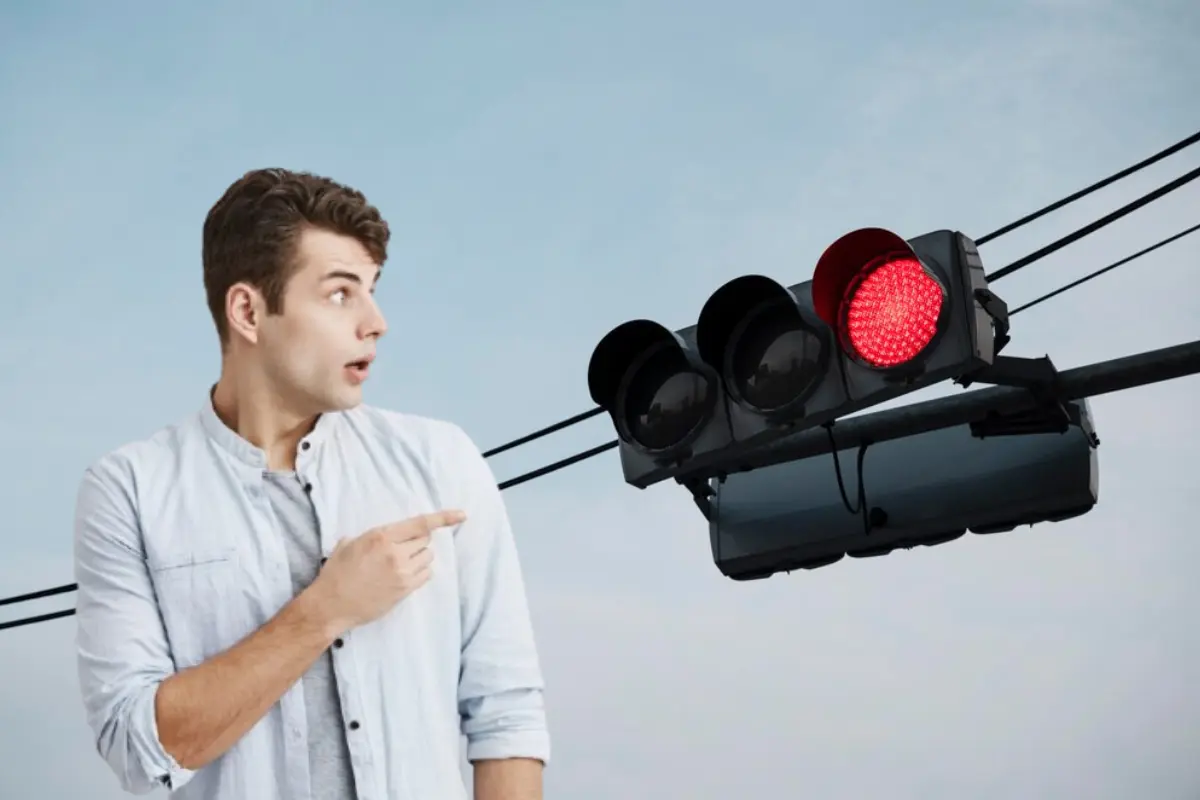 Hombre señalando la luz roja del semáforo.     Foto: Freepik editada en Canva.