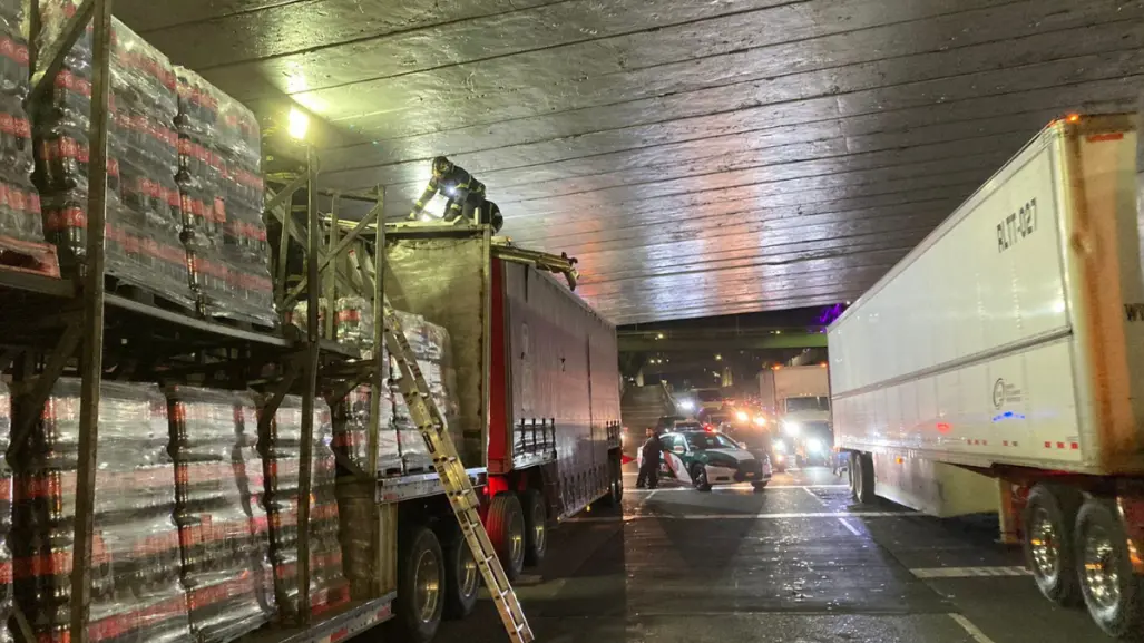 Tráiler cargado de refrescos, se atora bajo un puente por exceder altura permitida