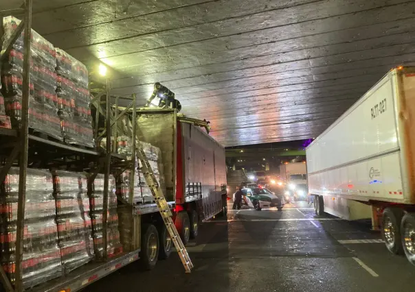 Tráiler cargado de refrescos, se atora bajo un puente por exceder altura permitida