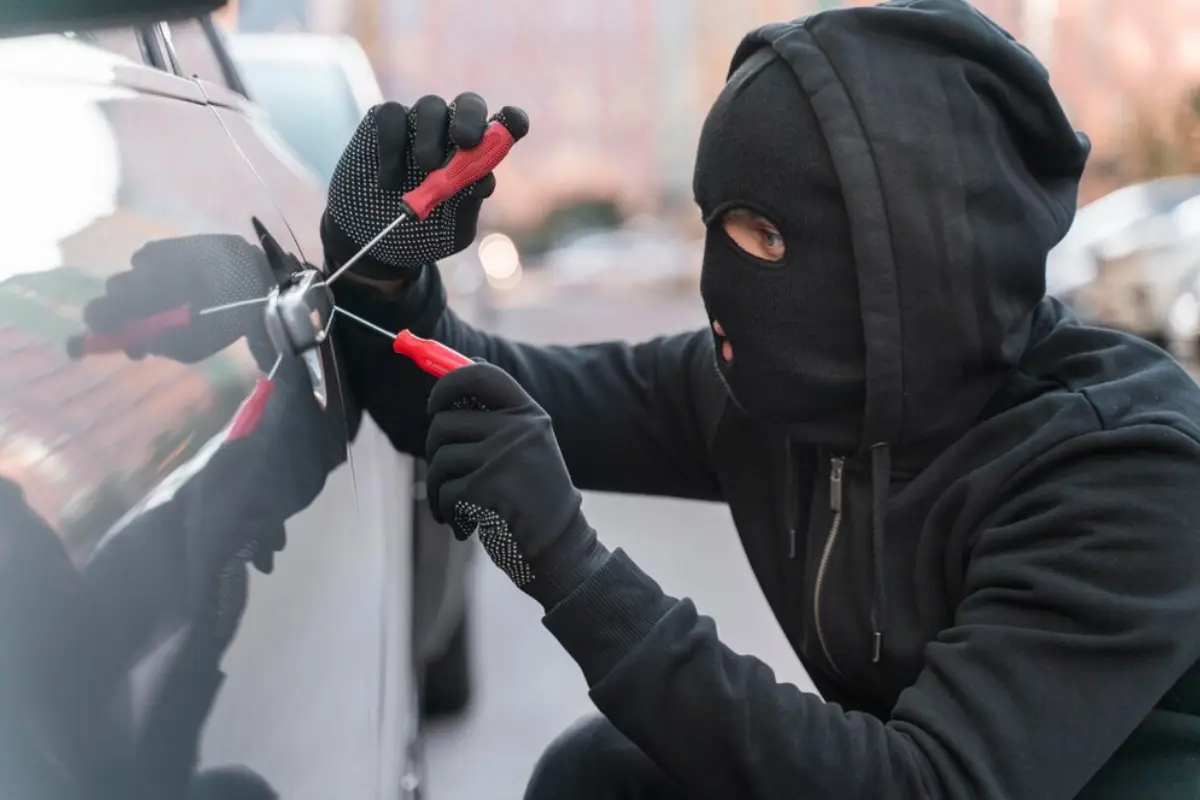 Ladrón de auto tratando de abrirlo.    Foto: Freepik, redimensionada en Canva.