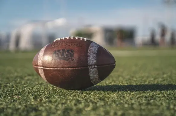 Balón de fútbol americano de marca Wilson en un campo para entrenar. Foto: Canva.