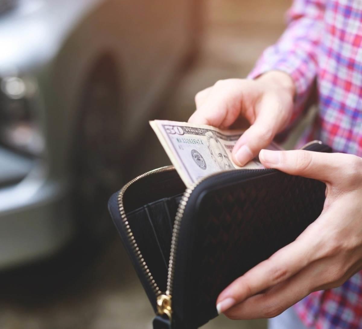 Persona sacando dinero para pagar el refrendo vehicular en Nuevo León. Foto: Canva.