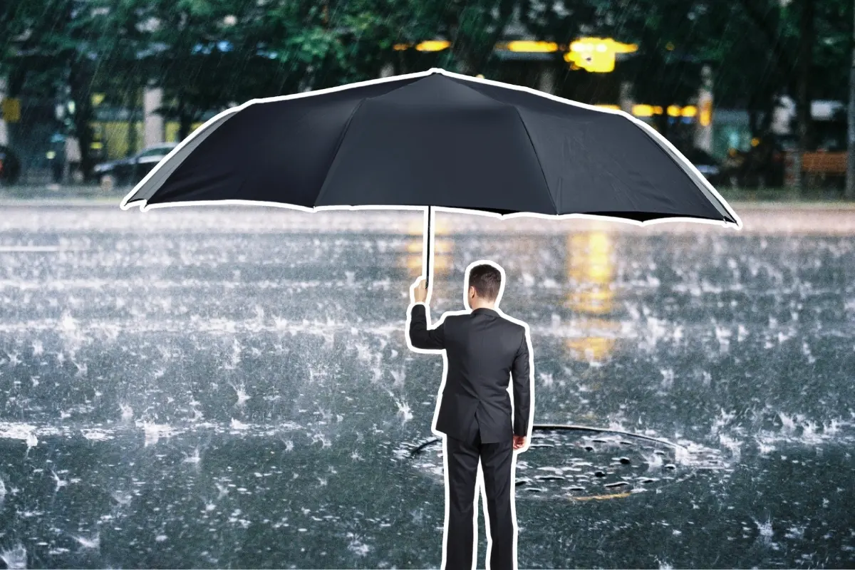 Lluvia en la calle y un hombre con paraguas. Foto: Canva