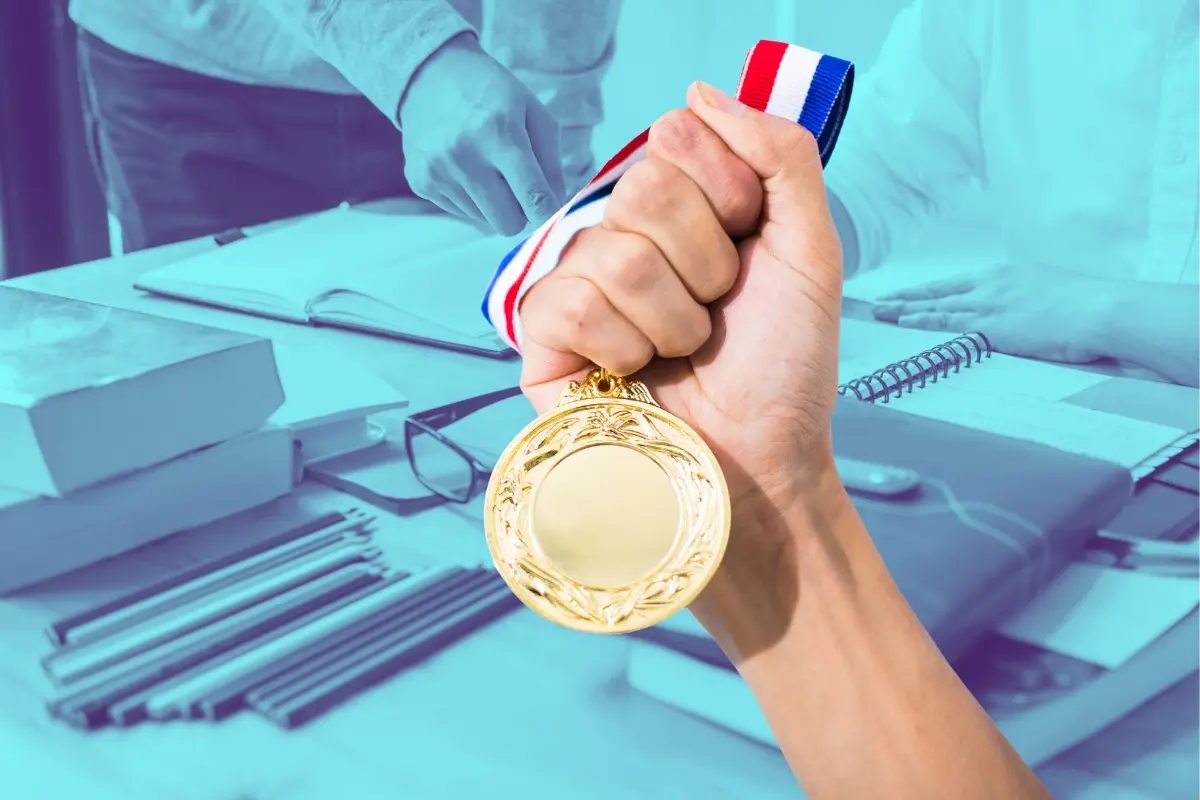 Una medalla y de fondo libros y útiles escolares. Foto: Canva