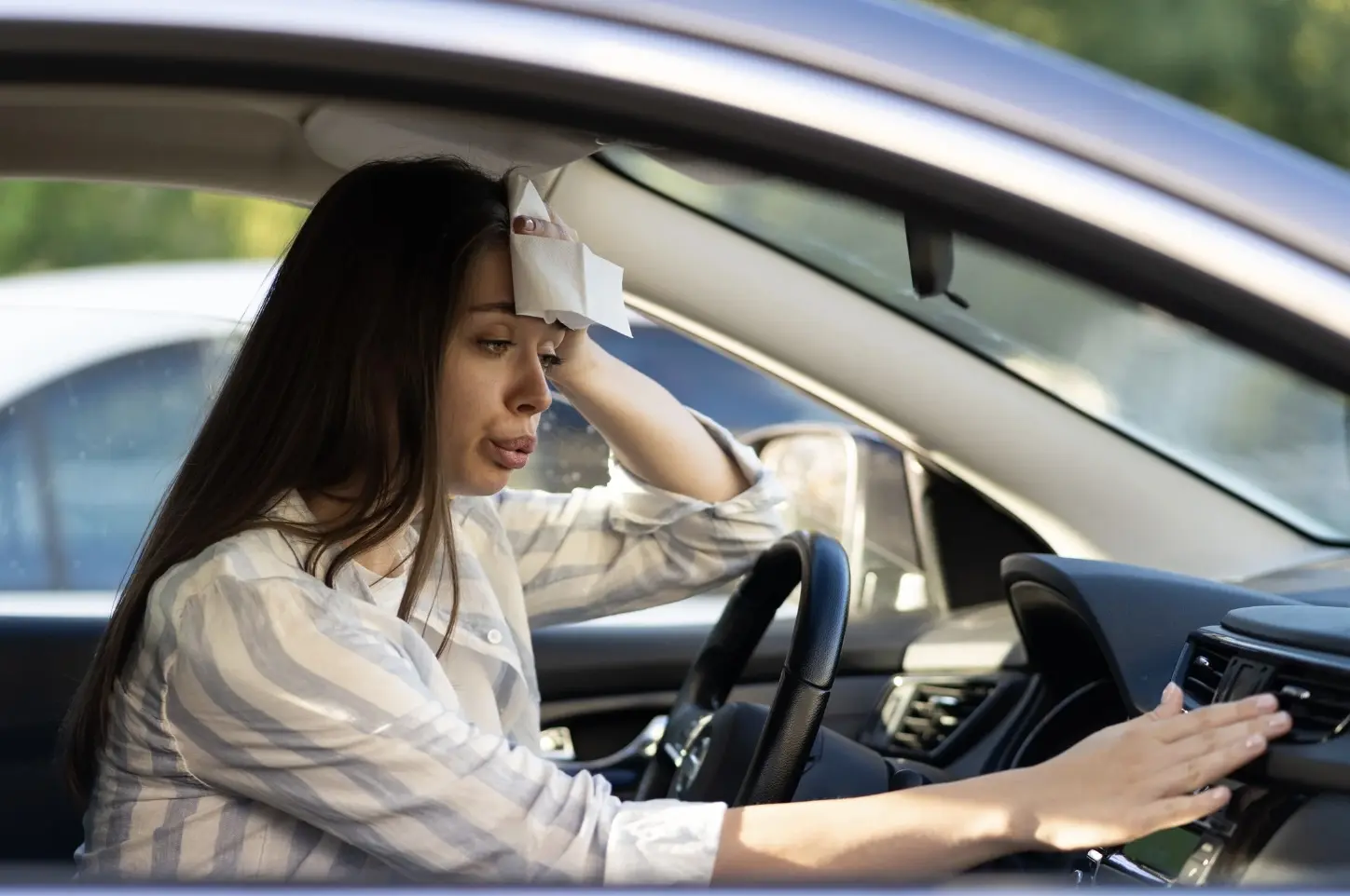 Mujer prendiendo el aire acondicionado de su auto a causa de las altas temperaturas Foto: Canva